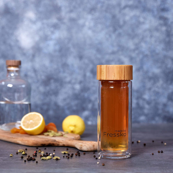 Spiced shandy mocktail inside fressko glass flask surrounded by spices and lemons