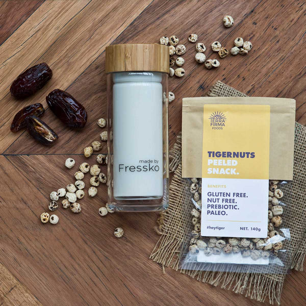 Tigernut Mylk Smoothie in glass fressko flask surrounded by dates and tigernuts